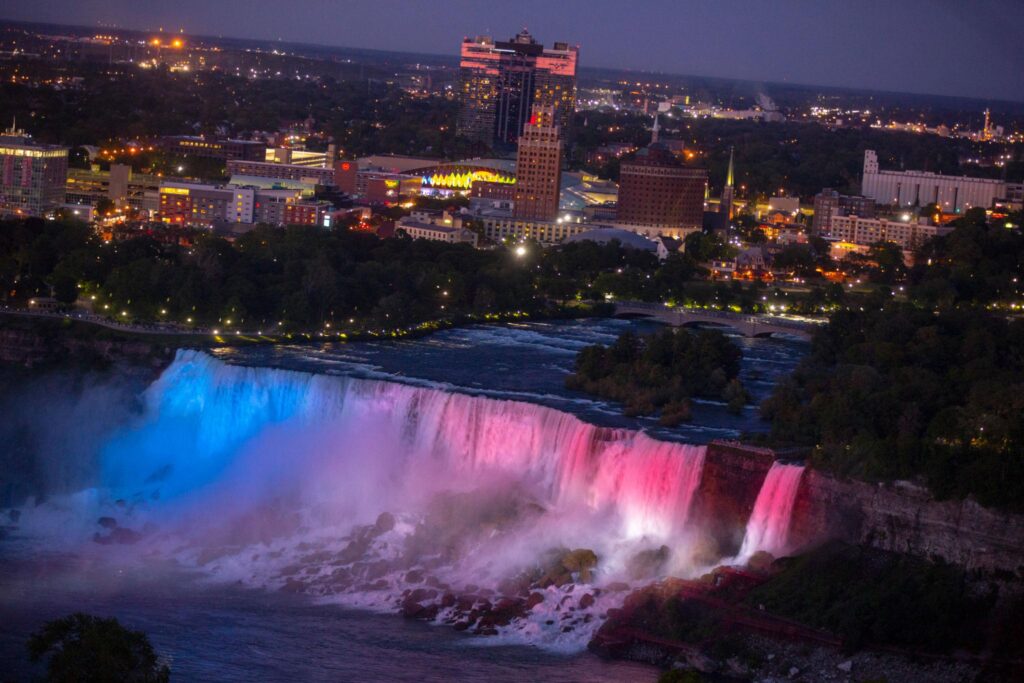 Night view of illuminated Niagara Falls during a Niagara Falls Evening Tour, part of guided Niagara Falls bus tours and Niagara Falls tour packages in Canada.